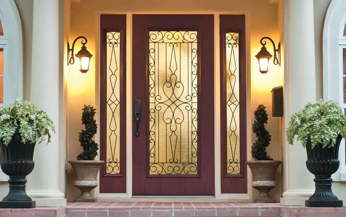 Front entry with ornate red double doors, gold glass center panel, and potted plants on either side.