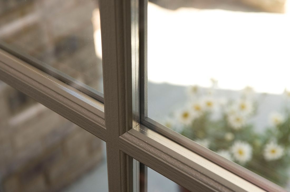 Window with white muntins and blurred flowers outside, sunlight glowing through the glass