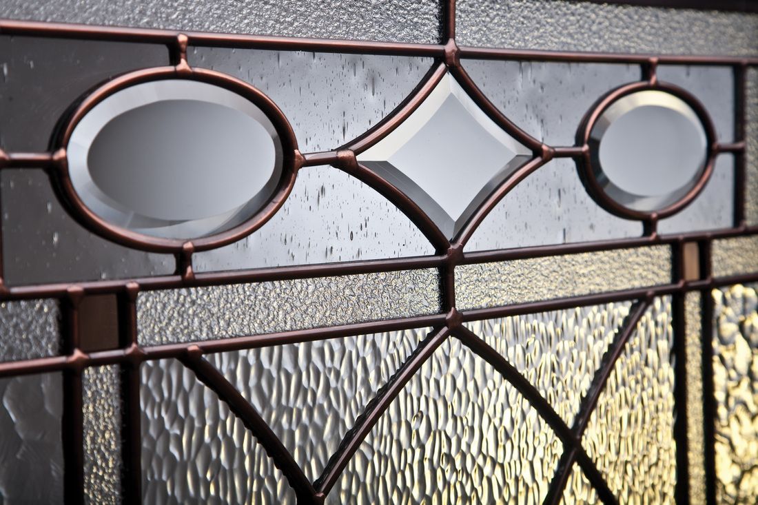 Decorative metal gate with oval and diamond patterns in front of frosted glass panels