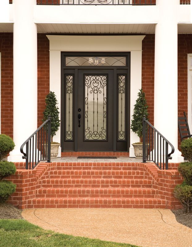 Front entrance with black double doors, brick steps, white columns, and trimmed shrubs