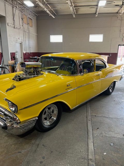 Yellow classic car parked in a garage, shown from the front-left side.