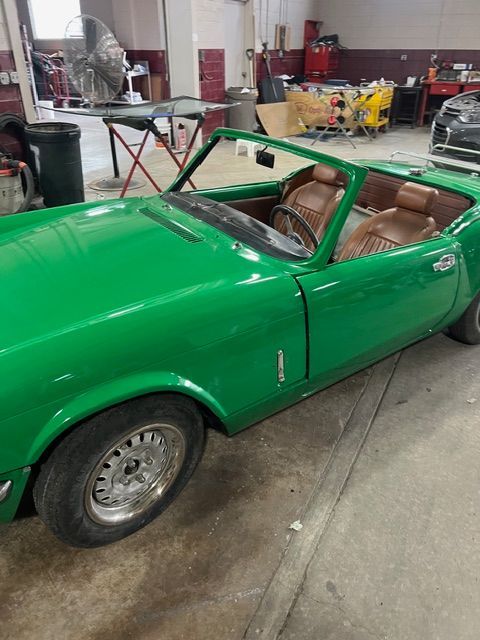 Bright green vintage convertible sports car parked indoors in a garage or workshop