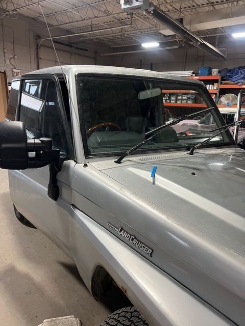 White pickup truck parked indoors in a warehouse, front side view with windshield wipers raised.