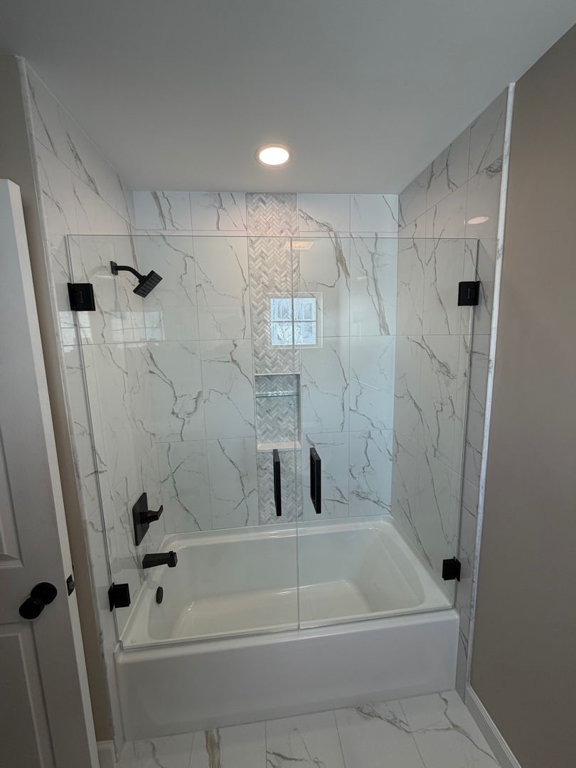 Small tiled bathroom shower-tub combo with white marble-look walls and black fixtures