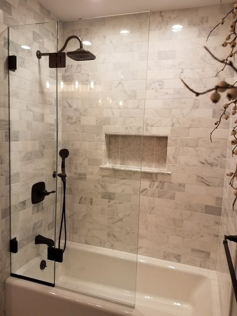 Modern bathroom with glass-enclosed bathtub shower and marble tile walls