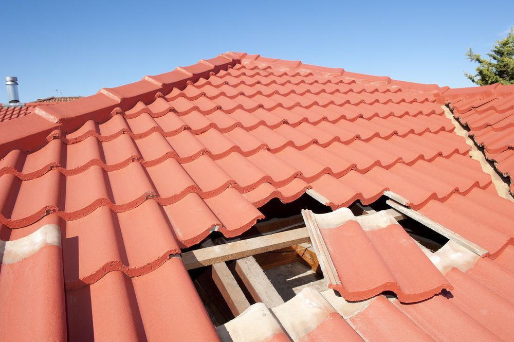 Red Tile Roof with A Hole Showing Exposed Wooden Beams — Geoff Hall Roofing in South West Rocks, NSW