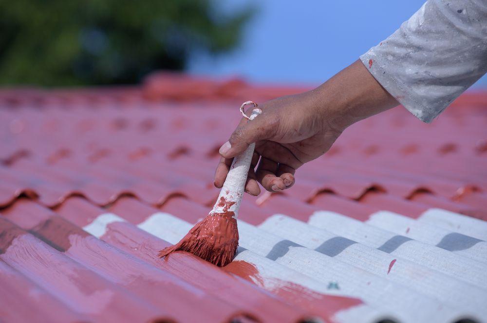Person painting a red roof with a paintbrush — Geoff Hall Roofing in Laurieton, NSW
