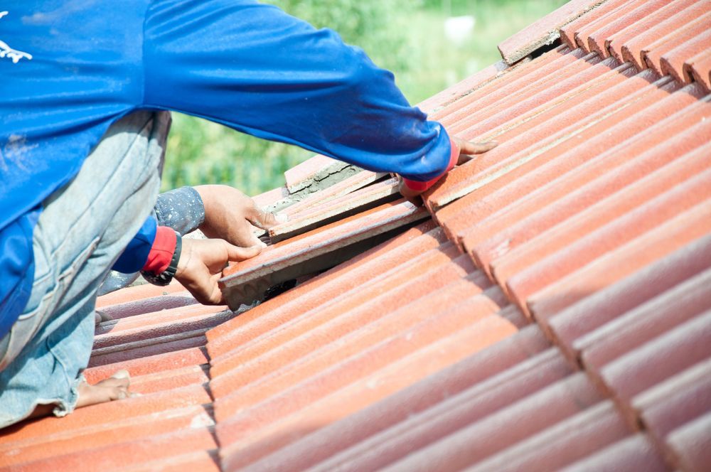 Person in blue shirt installing red roof tiles — Geoff Hall Roofing in Port Macquarie, NSW