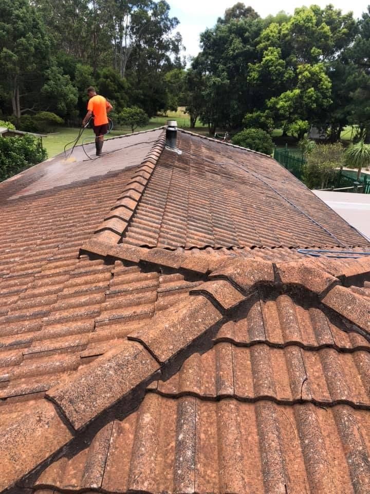 Worker Pressure Washing a Tiled Roof