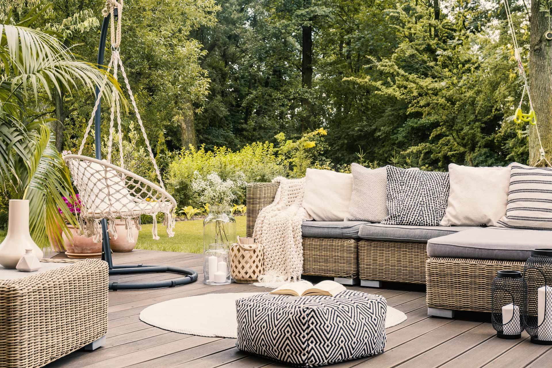 A wooden deck with wicker furniture and a hammock