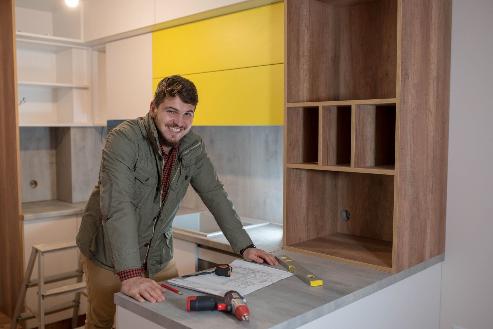 A man stands in a kitchen with tools, indicating a kitchen renovation in progress. A man stands in a kitchen with tools, indicating a kitchen renovation in progress.