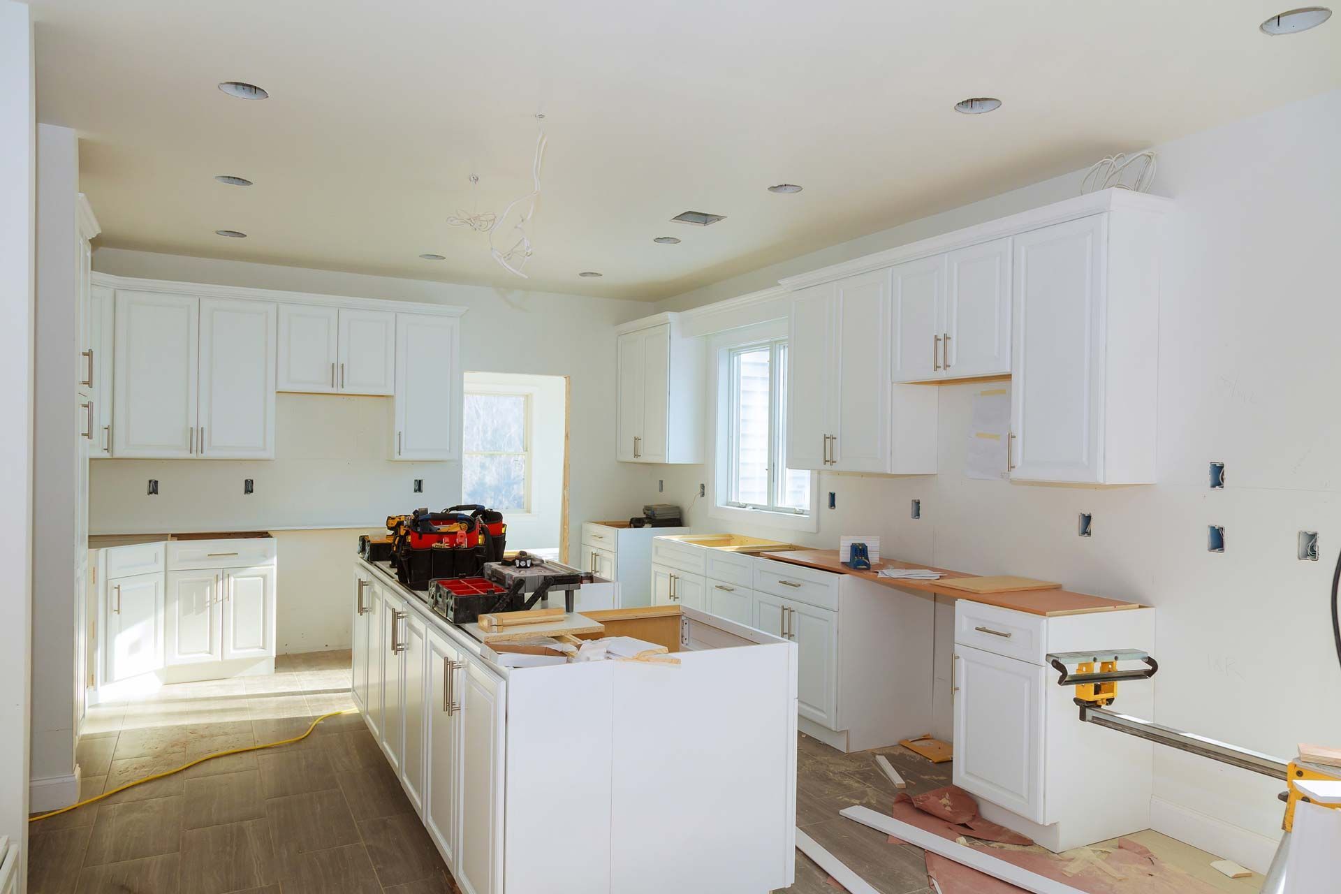 A kitchen under construction with white cabinets and a large island