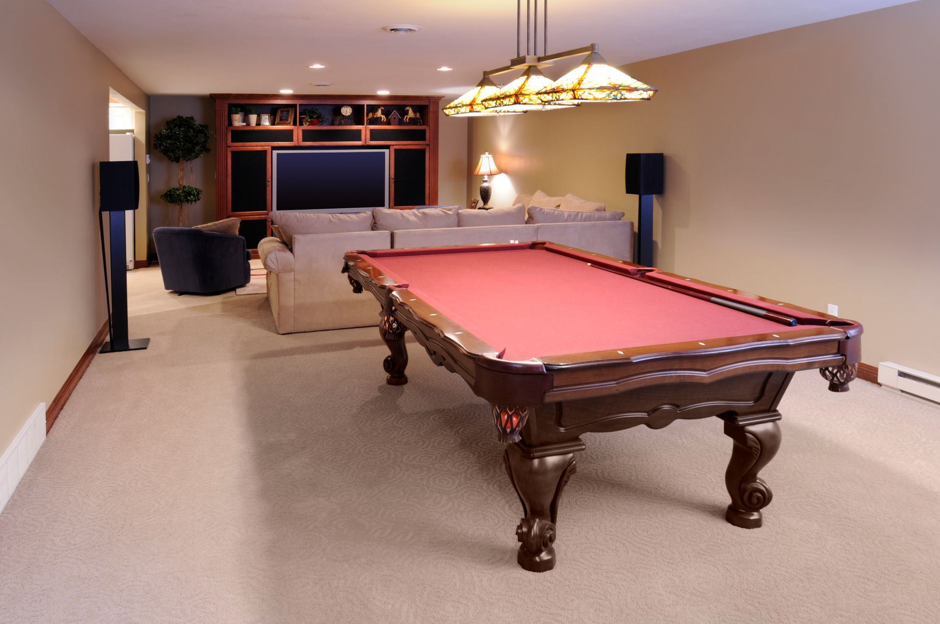 Pool table in a finished basement entertainment room, with seating, speakers, and a television.