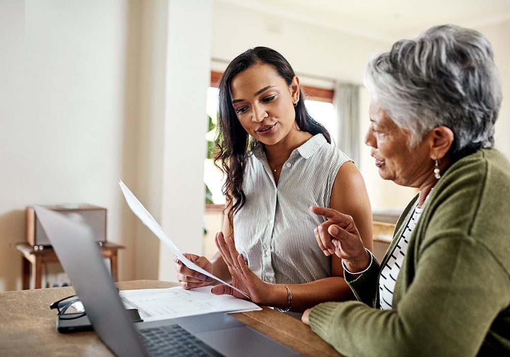 Woman Sitting and Explaining Financial Documents to Her Grandmother — Marlton, NJ — The Domenick Group