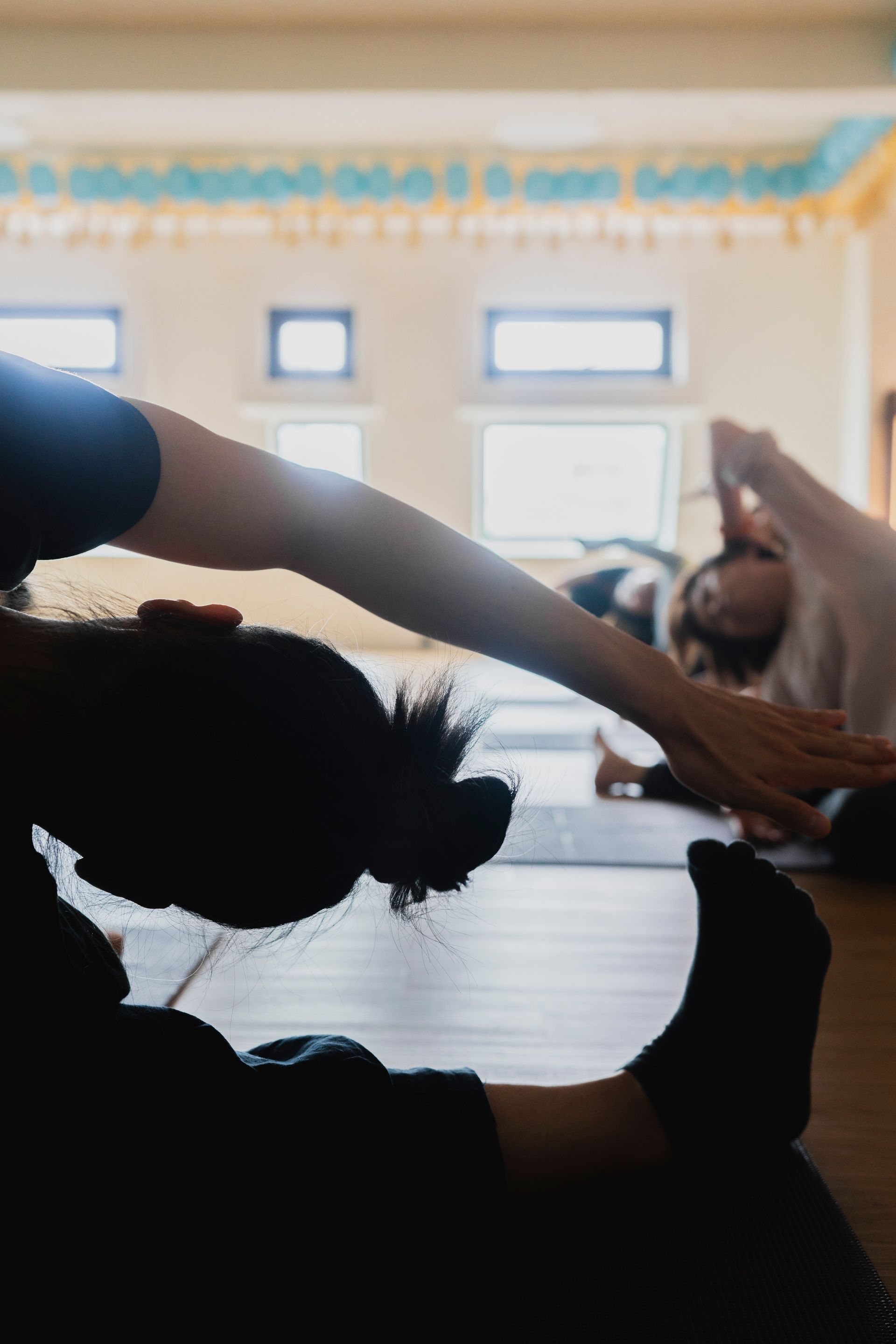 Silhouette of person stretching in yoga class; others in the background.