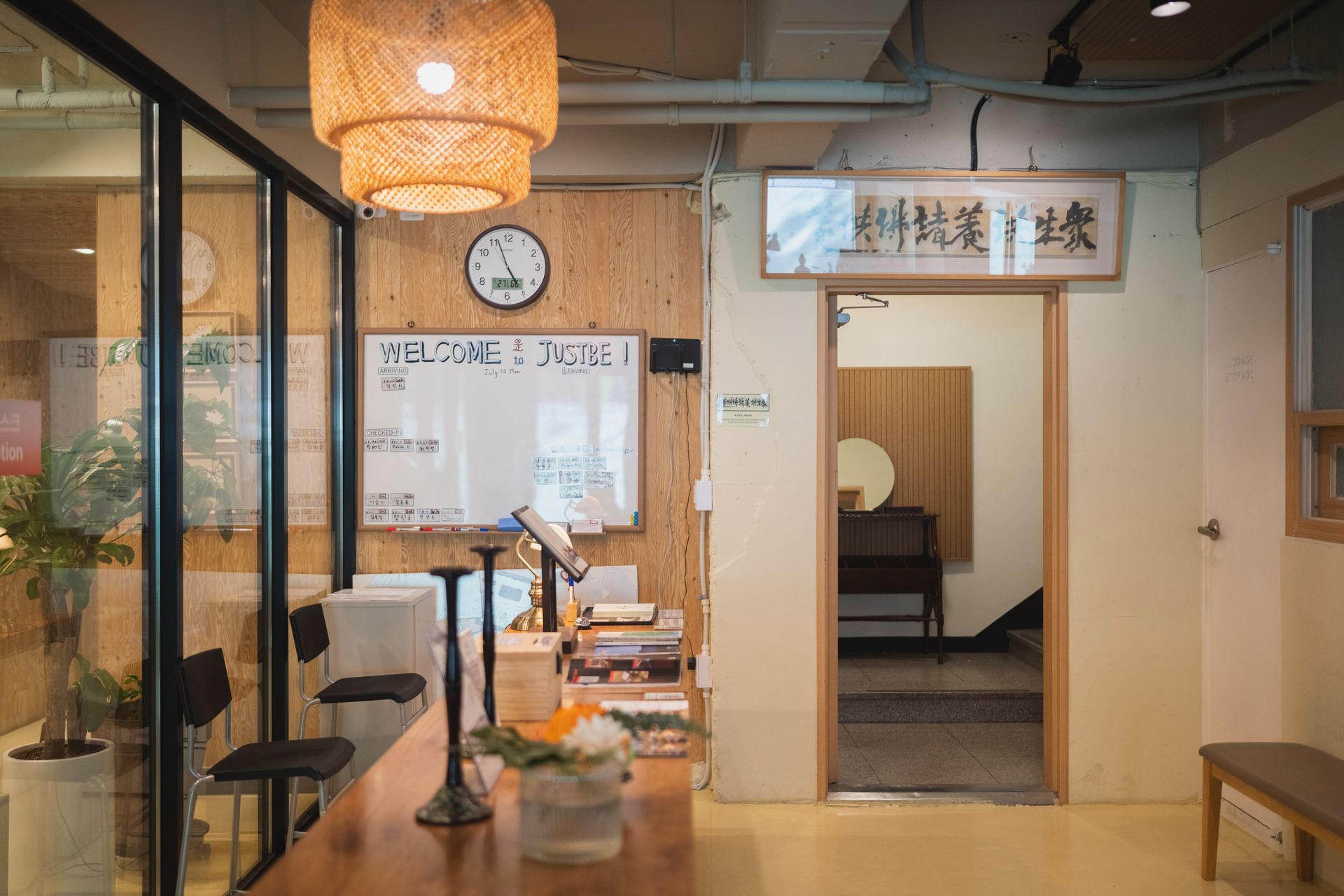 Interior with wooden accents, desk, clock, whiteboard, and entry to another space.
