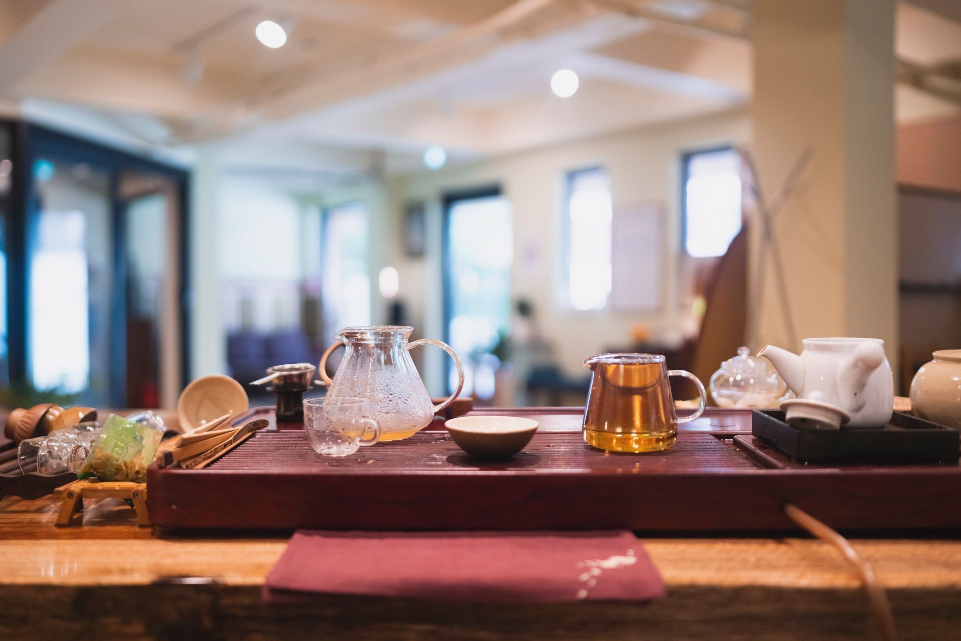 Tea ceremony setup on a wooden tray in a well-lit room. Teapot, cups, and utensils are arranged.