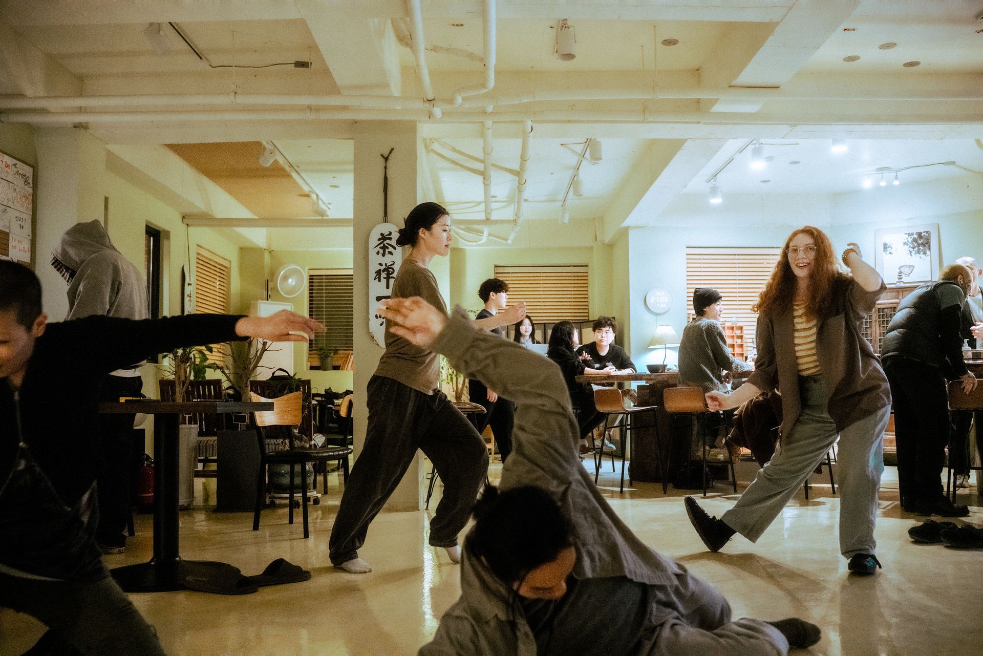 People practice martial arts in a brightly lit cafe.