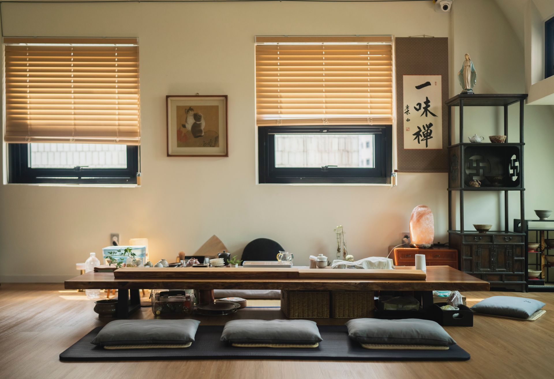 A minimalist tea room with a low table, cushions, and traditional decor, bathed in warm light.