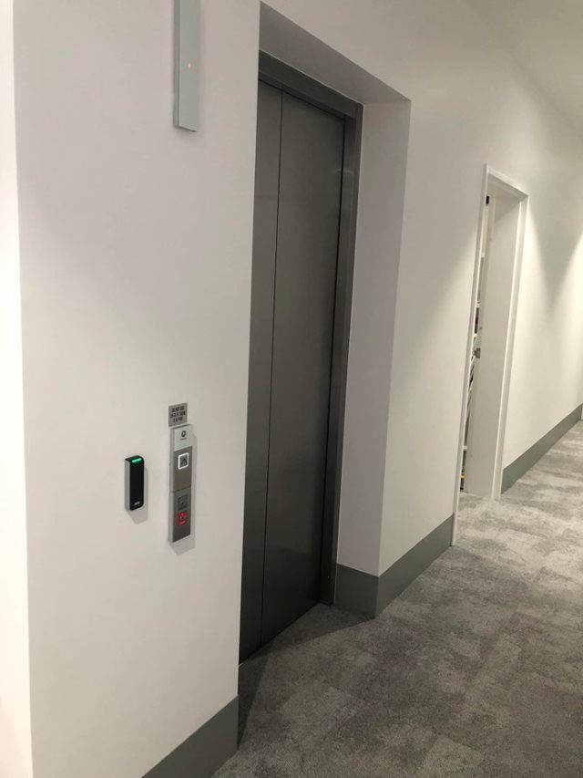 Elevator With Closed Metal Doors in a White Hallway — EBS NQ Electronic Building Systems in Kirwan, QLD
