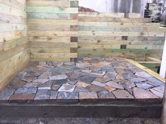 Stone tile floor with wooden wall construction in progress.