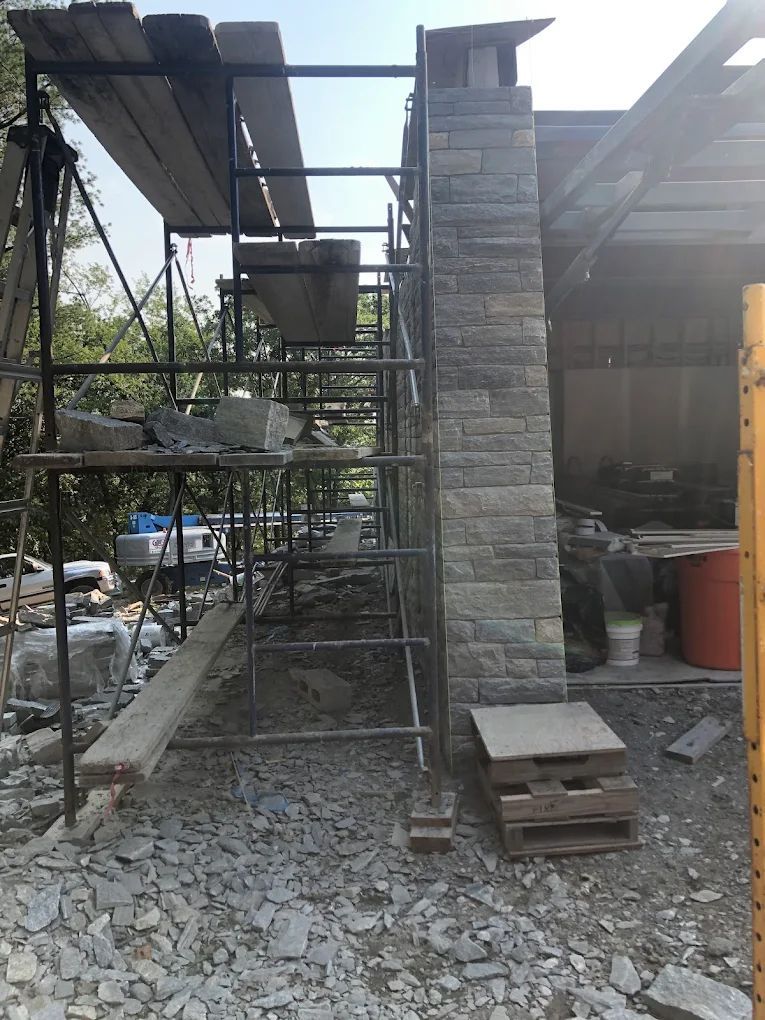 Stone chimney under construction with scaffolding.