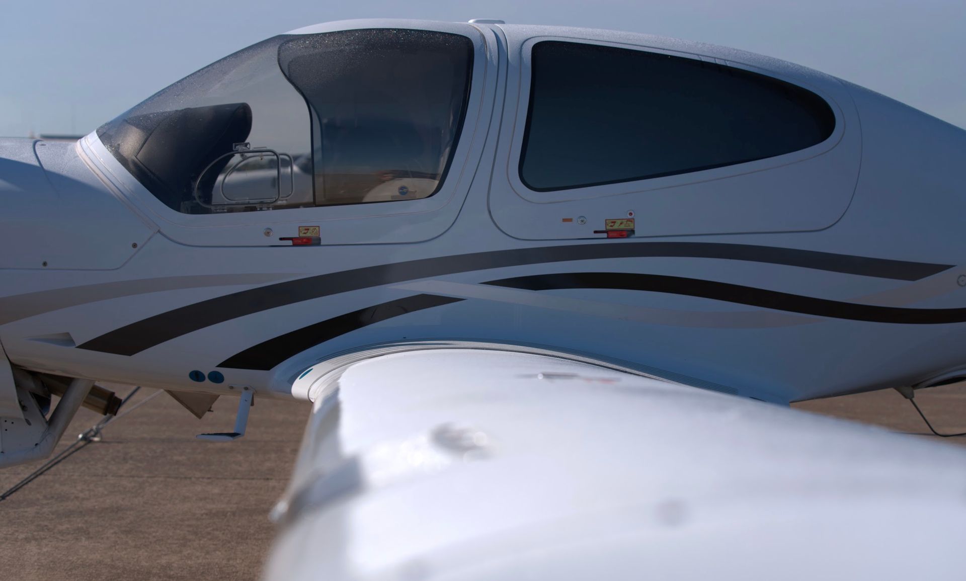 White airplane with curved windows and black stripe detail on a sunny day.