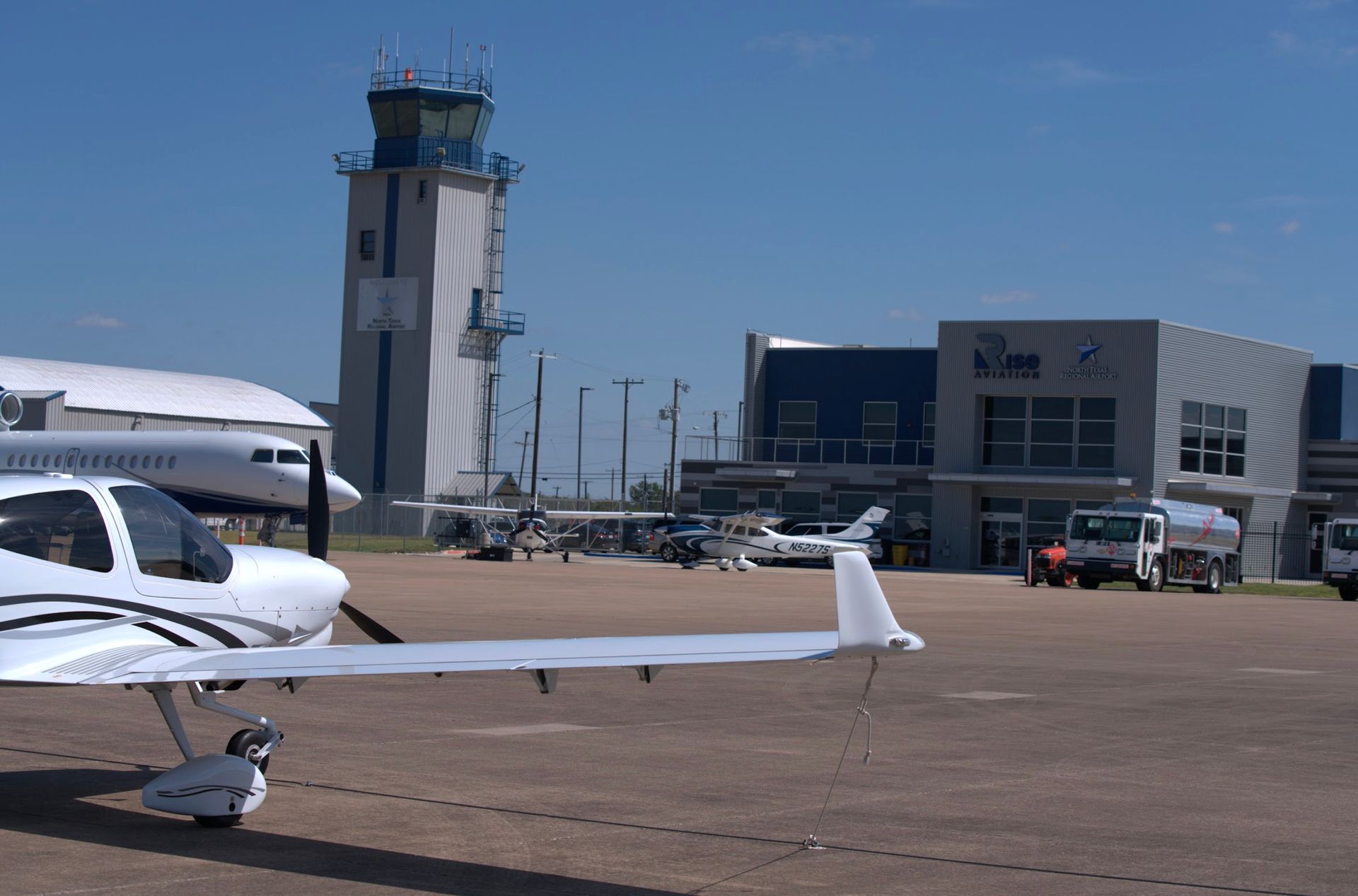 Airplane parked on tarmac with airport tower and terminal in background.