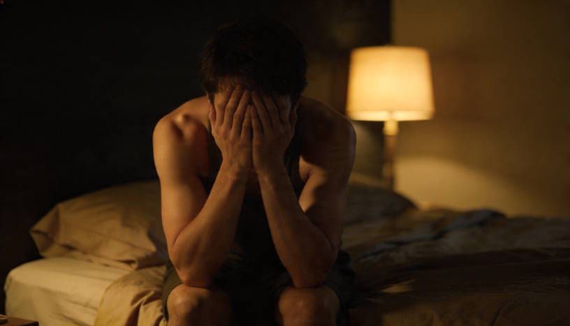 Dayton man sitting on edge of his bed at night, elbows on his knees, and hands on his face exhausted and cant sleep