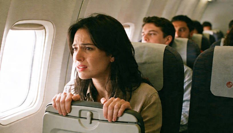 woman with a fear of flying gripping the airplane seat after boarding her plane