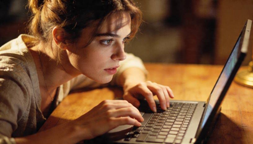 woman with a thoughtful expression on her face while she looks for answers on her laptop