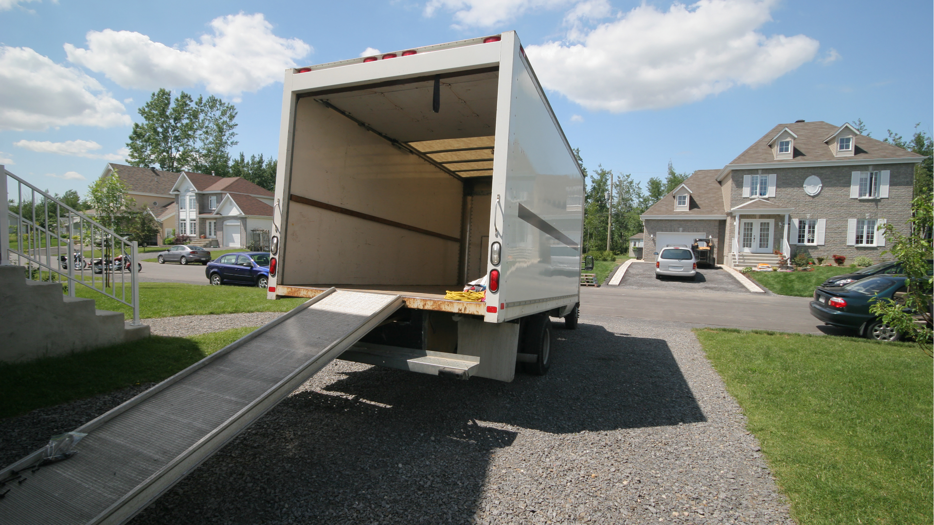 Two movers in blue uniforms carrying a large cardboard box near a white van.