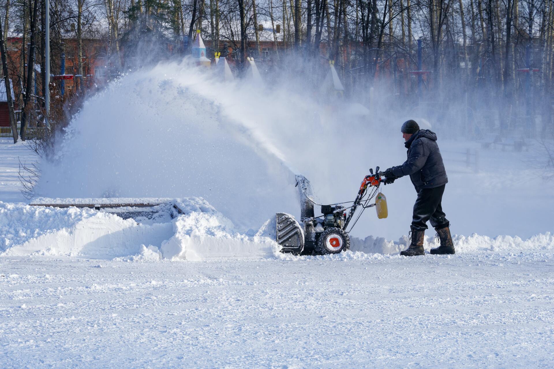 A man is using a snow blower to clear snow from the ground.