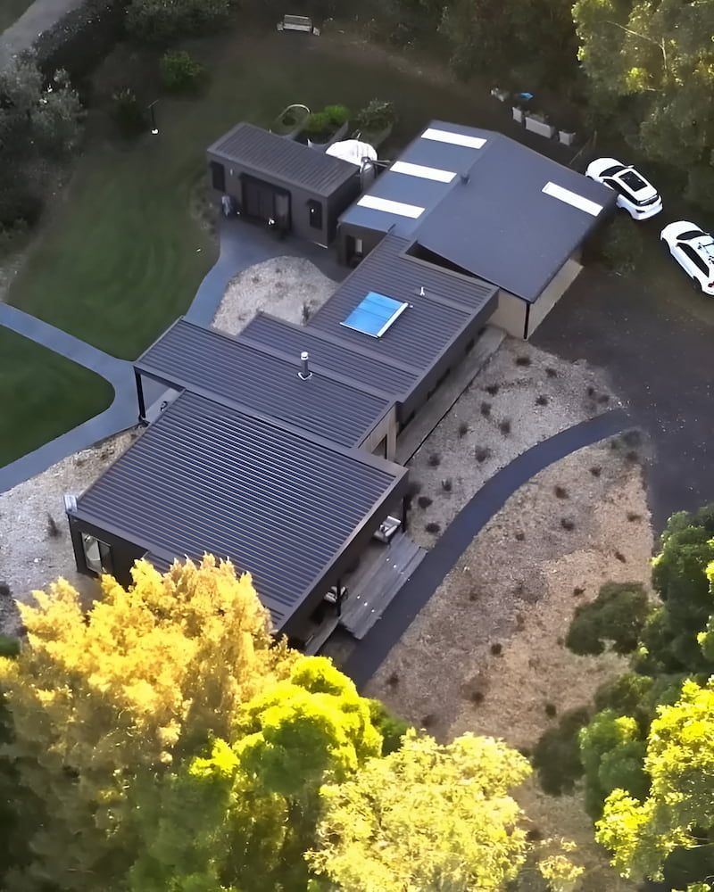 An Aerial View of a House With Cars Parked in Front of It — Metal Roofing by Matt Dwyer in Shellharbour, NSW