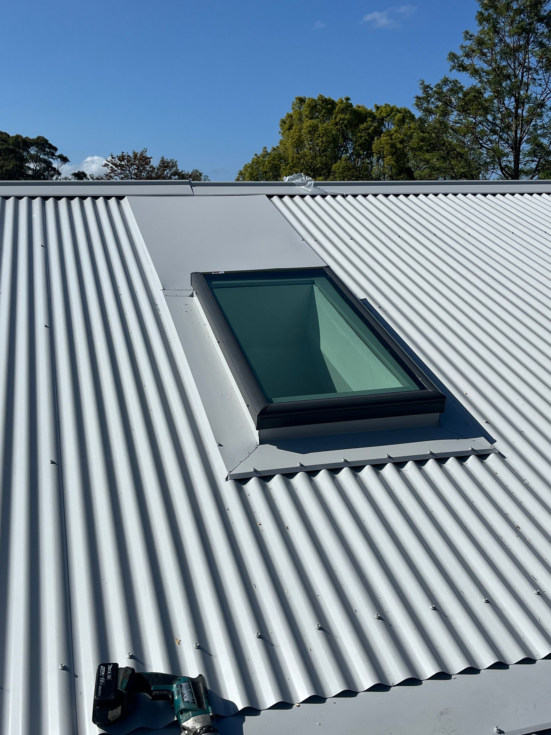 A Man is Installing a Skylight on a Roof — Metal Roofing by Matt Dwyer in Gerringong, NSW