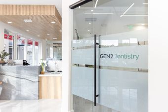 Bright dental clinic reception with glass doors and a wood-slat ceiling