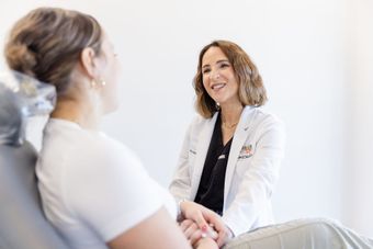 Doctor speaking with a seated patient in a bright clinic office