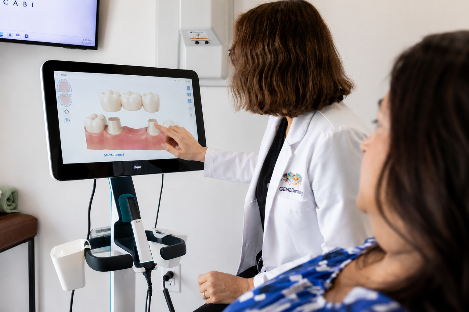 Dentist showing a tooth diagram on a screen to a seated patient