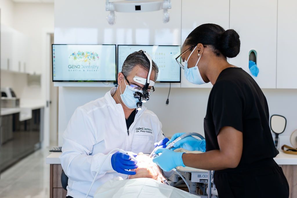 Dentist and assistant wearing masks and gloves treating a patient