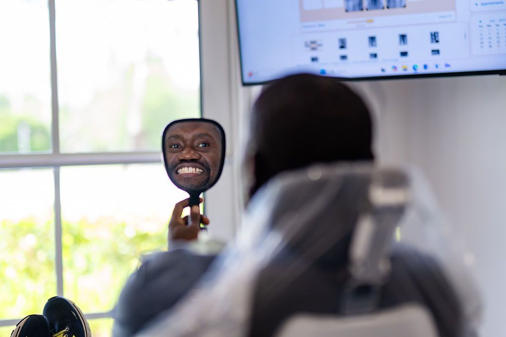 Patient checking their smile in a hand mirror from the dental chair