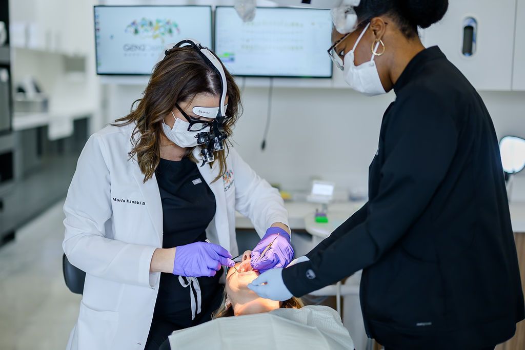 Dentist wearing magnifying loupes treating a patient with an assistant at GEN2 Dentistry