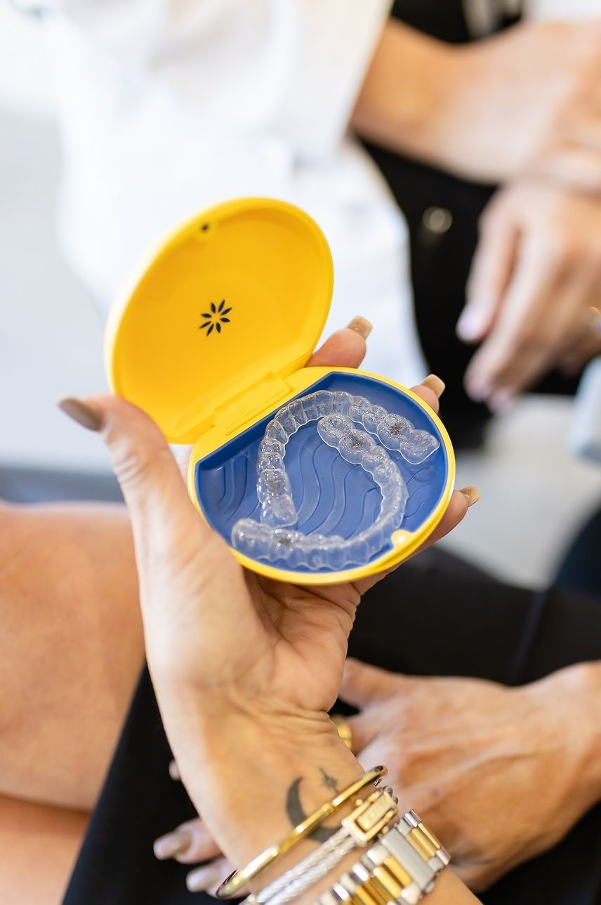 Dental professional holding a clear aligner model during a patient consultation.