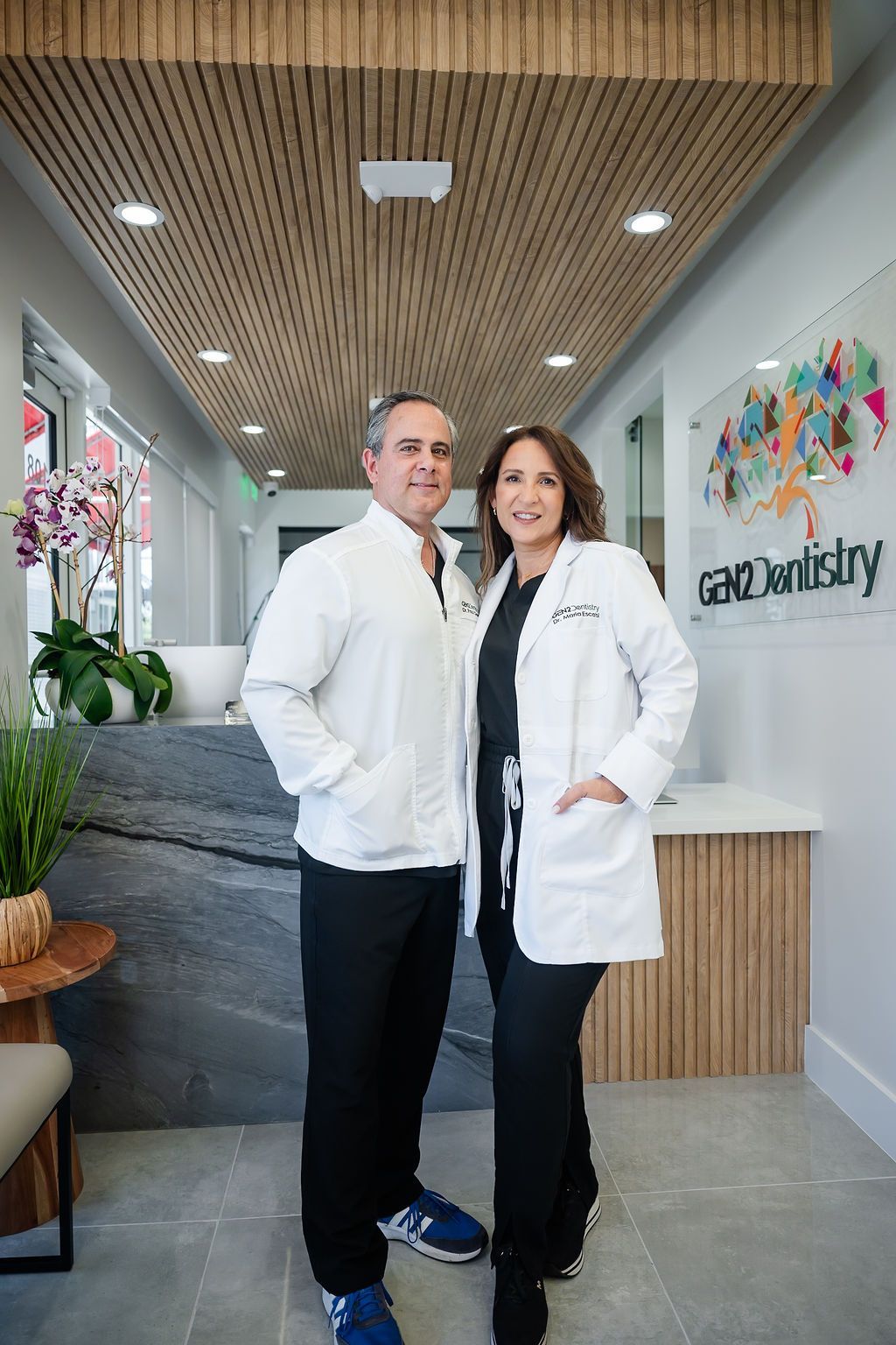 Two dentists in white coats standing in a modern dental office lobby.