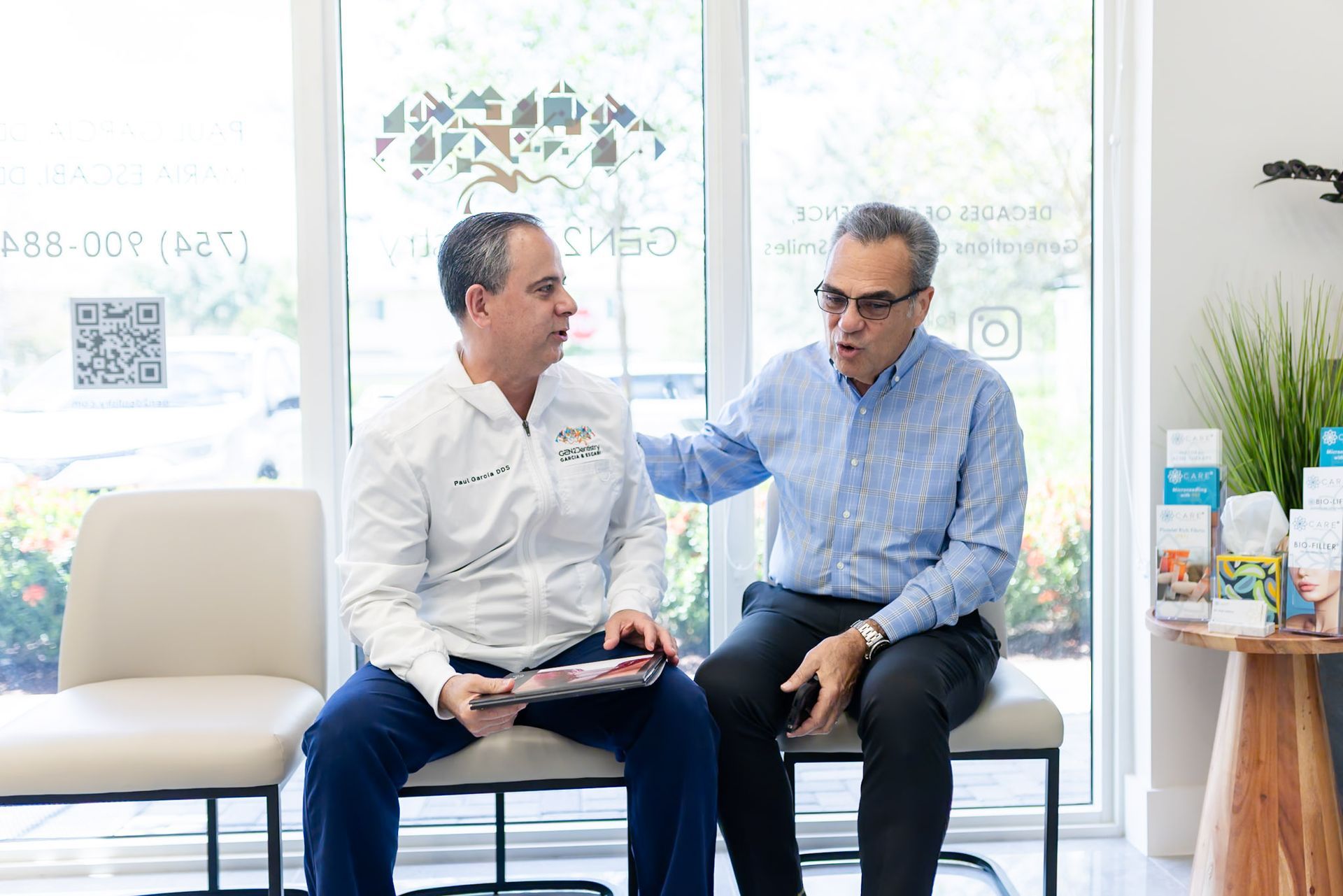 Dentist in a GEN2 Dentistry coat talking with a patient in the office lobby