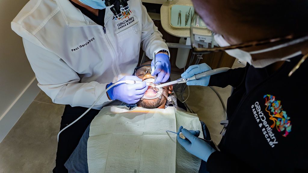 Dentist performing a procedure on a patient in a clinic, with bright overhead light and gloved hands.