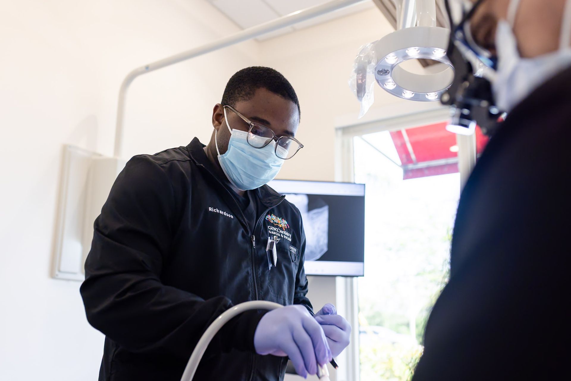 Dentist wearing a mask and gloves preparing equipment in a bright clinic room