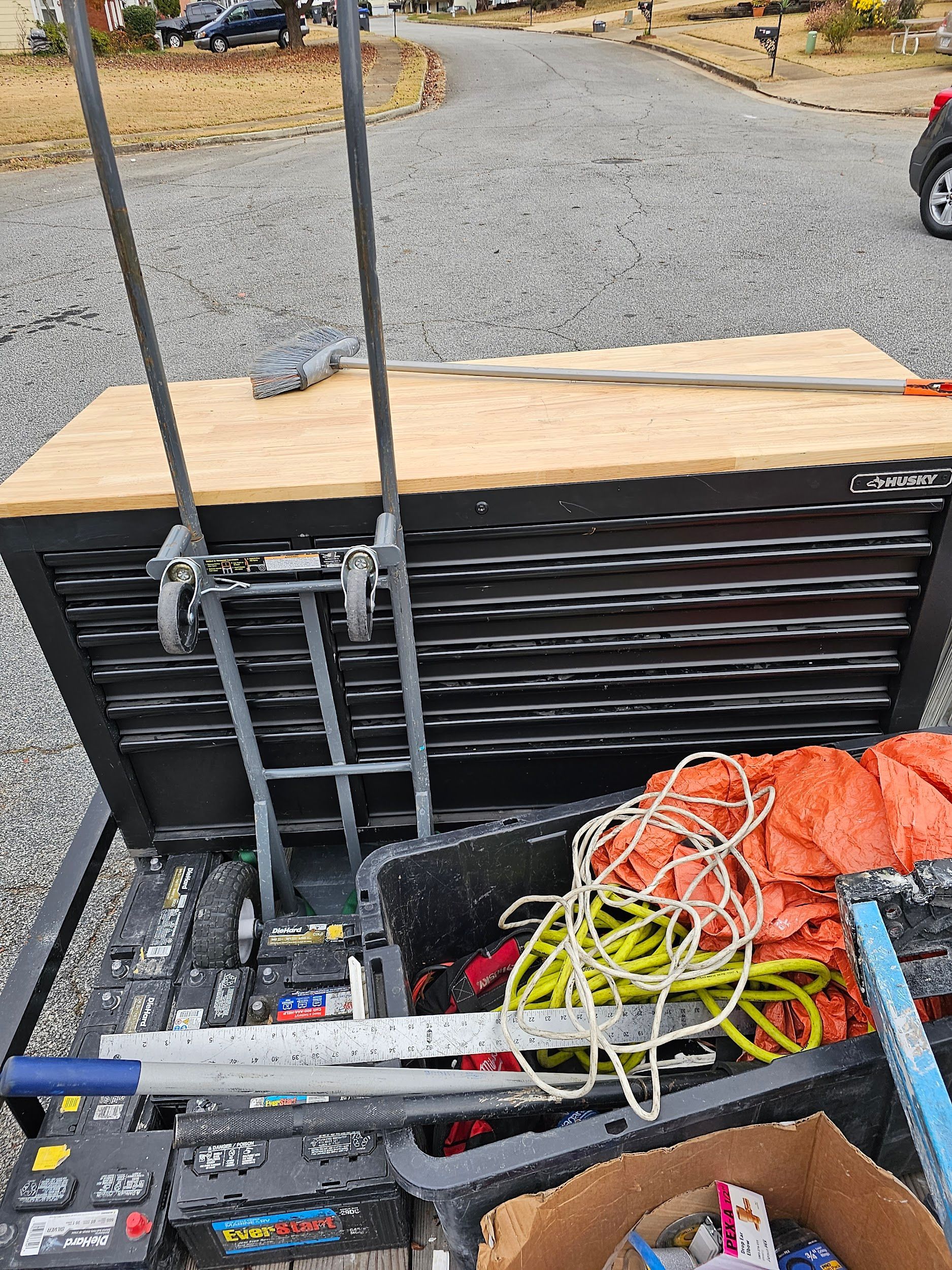 A toolbox filled with tools and a ladder is sitting on top of a trailer.