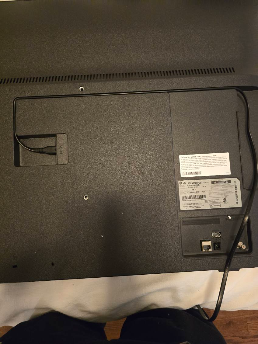 Back of a black television with labels and power cord.