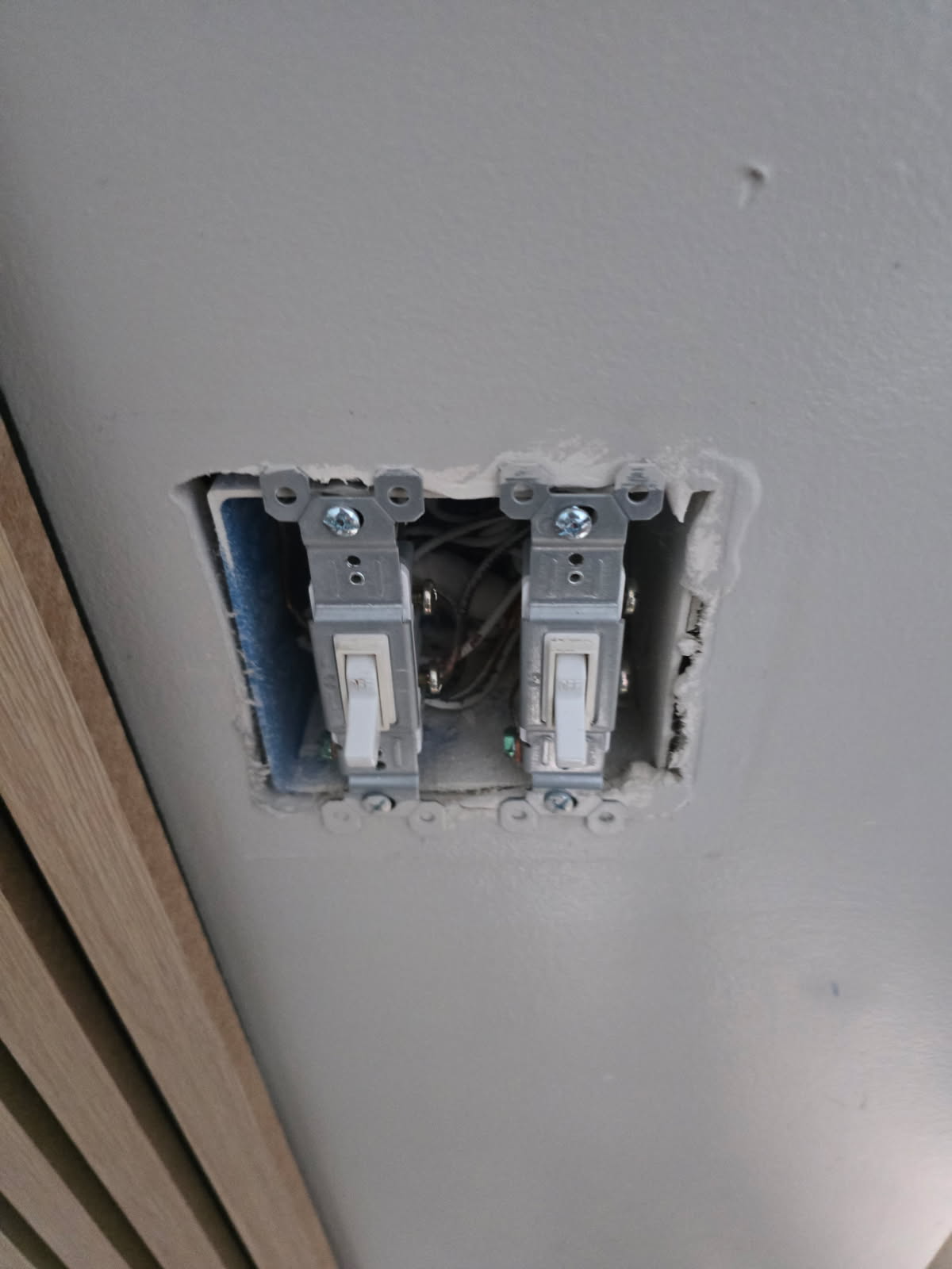 Two light switches installed in a recessed electrical box on a white wall.