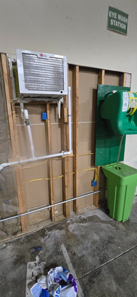 Wall-mounted utility equipment with green bins and pipes in a narrow outdoor alley.